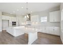 Stylish kitchen boasting white cabinets, modern appliances, and quartz countertops, complete with a spacious island at 10320 Longmeadow Ave, Parrish, FL 34219