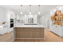 A modern, eat-in kitchen with white cabinets, stainless steel appliances, and a stylish wood-paneled island at 11508 Sage Canyon Dr, Riverview, FL 33578