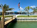 Beautiful waterfront home with a pool, dock, and outdoor seating area under the American and POW flags at 12300 4Th E St, Treasure Island, FL 33706