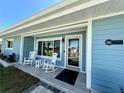 Inviting front porch with rocking chairs, stylish tiles, and light-blue wood siding with white trim at 12300 4Th E St, Treasure Island, FL 33706