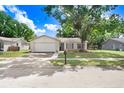 Charming single-story home with a well-maintained lawn, mature tree, and an attached two-car garage at 12910 Leadwood Dr, Riverview, FL 33579