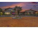 Stunning two-story home at sunset featuring brick accents, mature trees, fountain, and a brick driveway at 2309 Cypress Walk Way, Ruskin, FL 33570