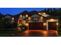 A beautiful home's facade is illuminated at night, accentuating the stonework and landscaping at 29118 Picana Ln, Wesley Chapel, FL 33543