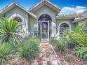Inviting home front with a brick walkway leading to the arched doorway entrance and lush, manicured landscaping at 2973 Spring Oak Ct, Palm Harbor, FL 34684
