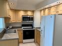 Well-maintained kitchen featuring light wood cabinets, updated appliances, and granite countertops at 400 Island Way # 1402, Clearwater Beach, FL 33767