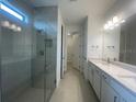 Bright bathroom with double vanity sinks, stone countertops, a glass-enclosed shower, and modern fixtures at 5014 Coastal Oak Ct, Lakewood Ranch, FL 34211