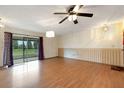 Open living room featuring hardwood floors, ceiling fan, sliding glass doors, and a white wall at 5250 Brody Blvd, Wimauma, FL 33598