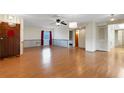 Spacious living room featuring hardwood floors, a ceiling fan, natural light and a wooden door at 5250 Brody Blvd, Wimauma, FL 33598