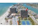 Aerial view of a high-rise condominium building next to the beach, with amenities like tennis courts and a pool at 7600 Bayshore Dr # 1201A, Treasure Island, FL 33706