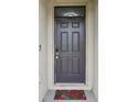 A close-up of a gray front door, digital lock, and seasonal poinsettia doormat at 10233 Opaline Sky Pl, Riverview, FL 33578