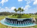 Mirada community entrance features a scenic water fountain, lush landscaping, and beautiful palm trees under a clear blue sky at 10381 Tupper Cay Dr, San Antonio, FL 33576