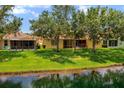 Relaxing backyard view featuring lush green grass, mature trees, serene water, and screened patio at 11559 Captiva Kay Dr, Riverview, FL 33569