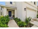 Inviting front entrance with a blue door, tidy landscaping, and a covered porch at 13686 Whiskey Daisy Dr, Dade City, FL 33525