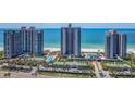 Aerial view of oceanfront condos with swimming pool, tennis courts, and mature palm trees at 1520 Gulf Blvd # 1505, Clearwater Beach, FL 33767