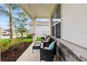 Seating area on a covered front porch that has a stone accent wall at 1675 Bering Rd, Wesley Chapel, FL 33543