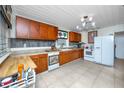 Traditional kitchen with wooden cabinets, white appliances, and tiled flooring at 1683 Pine St, Largo, FL 33774