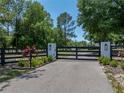 Elegant black fence gate with stone pillars and decorative lanterns marking the driveway entrance at 18577 Clay Hill Rd, Dade City, FL 33523