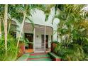 Welcoming front entrance with a screened-in porch and vibrant tropical landscaping at 214 Scotland St, Dunedin, FL 34698