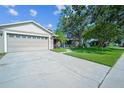 Front exterior of home features attached two car garage, well-kept lawn, and mature trees at 2507 Dewberry St, Valrico, FL 33596