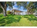 Side yard featuring manicured lawn, mature shade trees, and fenced enclosure at 2507 Dewberry St, Valrico, FL 33596