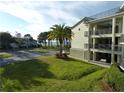 Condo exterior with balconies, well-maintained lawn, tropical palm tree, and partial water view at 2700 Bayshore Blvd # 5210, Dunedin, FL 34698