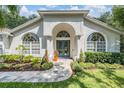 Elegant home featuring an arched entryway, meticulously landscaped garden beds, and a pristine walkway at 4797 Stonebriar Dr, Oldsmar, FL 34677
