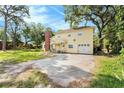 Back yard view of a two-story home featuring a spacious yard, patio, and mature trees at 6024 90Th N Ave, Pinellas Park, FL 33782