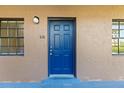 Close-up of a vibrant blue front door with classic hardware and textured stucco walls at 6100 Gulfport S Blvd # 114, Gulfport, FL 33707