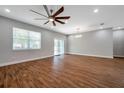 Open-concept living room with wood-look tile flooring, sliding doors to lanai, and modern ceiling fan at 8608 N Arden Ave, Tampa, FL 33604