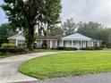 Classic brick home with a covered porch, well-maintained lawn, and a circular driveway on a foggy morning at 1002 W Pinedale Dr, Plant City, FL 33563