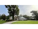 Charming single-story brick home with lush landscaping, a covered porch, and a circular driveway at 1002 W Pinedale Dr, Plant City, FL 33563