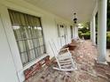 Inviting brick front porch with white rocking chairs, columns, and a view of the front yard at 1002 W Pinedale Dr, Plant City, FL 33563