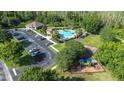 Aerial view of community amenities including a pool, playground, parking, and a recreation building surrounded by lush trees at 12136 Luftburrow Ln, Hudson, FL 34669