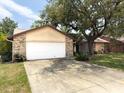 View of the 2-car garage and driveway, and partial view of the single story home at 1228 Rainbrook Cir, Valrico, FL 33596