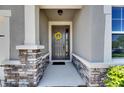 Welcoming front entry with stone accents and a decorative wreath adorning the gray front door at 12957 Satin Lily Dr, Riverview, FL 33579