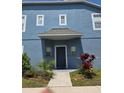 Two-story townhouse featuring a blue exterior with a covered entrance and manicured landscaping at 13157 Kings Crossing Dr, Gibsonton, FL 33534