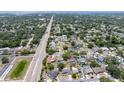 Wide aerial view of a residential neighborhood with tree-lined streets and various home styles, extending to the water at 1818 Willow Oak Dr, Palm Harbor, FL 34683