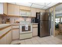 Functional kitchen featuring appliances, light wood cabinets, and tile floors at 4550 Cove Cir # 1003, St Petersburg, FL 33708