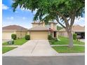 Charming two-story home with a spacious driveway and lush front yard, partially shaded by a mature tree at 5525 Turtle Crossing Loop, Tampa, FL 33625