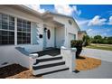 Inviting front porch with gray stairs, a white door, and white and blue accents at 5642 9Th N Ave, St Petersburg, FL 33710