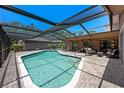 Beautiful screened-in pool area with a brick patio, multiple seating options, and clear blue water, perfect for relaxation at 6101 Willow Oak Cir, Bradenton, FL 34209