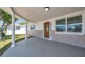 Covered front porch with decorative columns, front door, and well maintained landscaping at 6309 7Th Ave, New Port Richey, FL 34653