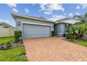 Charming single-story home featuring a brick driveway, two-car garage, and well-maintained landscaping at 751 Cajeput Loop, Tarpon Springs, FL 34689