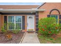 Close up of the front entrance with a white door, black shutters, and green flowered bushes at 7591 121St Ter, Largo, FL 33773