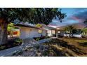 Charming single-story home at dusk featuring a well-maintained front yard, beautiful landscaping, and a welcoming entrance at 829 Riverside Dr, Tarpon Springs, FL 34689