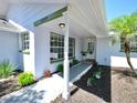 Welcoming front porch with well-manicured landscaping, hanging plants, and exterior lighting at 829 Riverside Dr, Tarpon Springs, FL 34689
