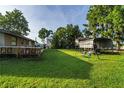 Large, grassy backyard featuring mature trees, play structure and chicken coop at 10818 Land O Lakes Blvd, Land O Lakes, FL 34638