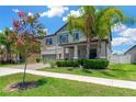 Inviting two-story home with a well-kept lawn, brick driveway, and beautiful palm trees and flowering tree at 11612 Sunburst Marble Rd, Riverview, FL 33579