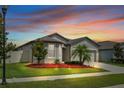 Inviting home with manicured lawn, landscape lighting and mulch beds under a vibrant twilight sky at 12653 Palapa Loop, Spring Hill, FL 34610