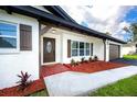 Inviting front entrance with a decorative door, fresh landscaping, and manicured lawn at 1873 Murray Ave, Clearwater, FL 33755